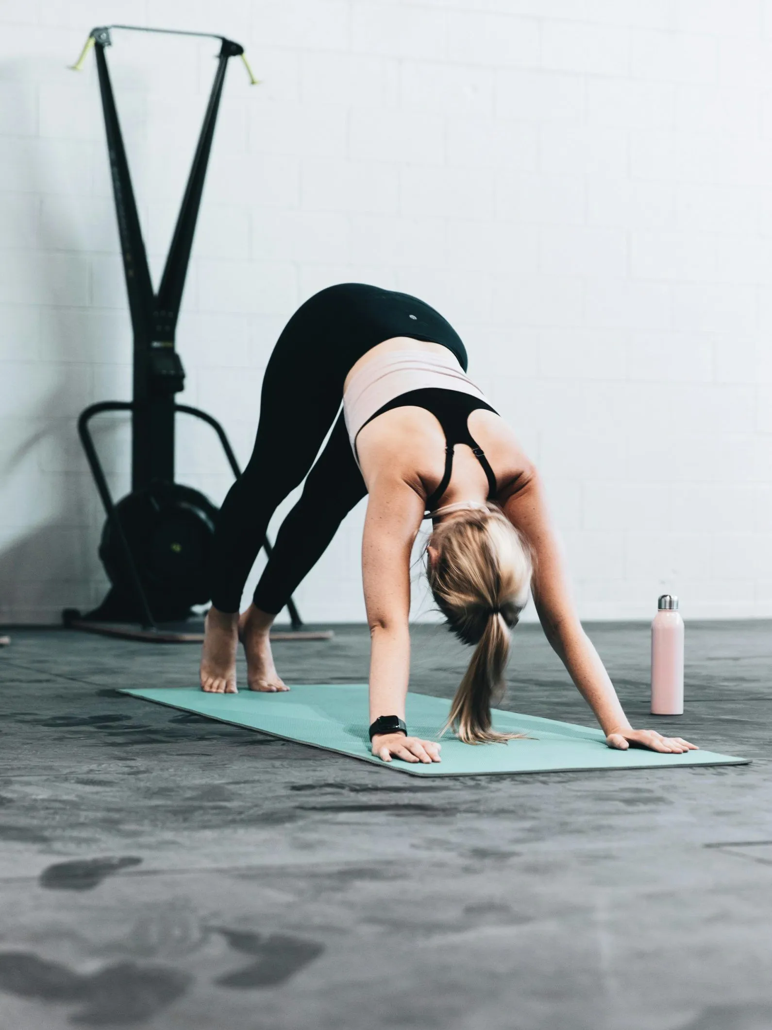 Athlete stretching on a mat beside a cable machine